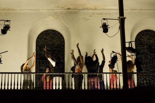 A group of dancers on the inside balcony of the St. Mark's Church sanctuary all moving with arms raised in an energetic gesture.