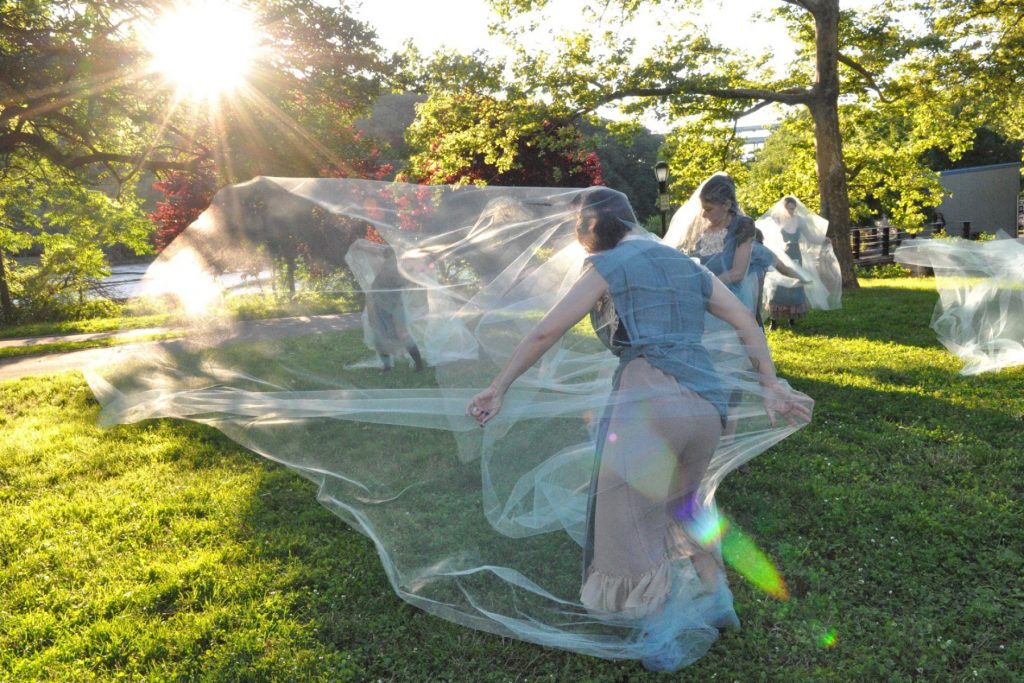 Sunlight shining on dancers through diaphanous fabric