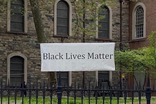 A white banner that reads Black Lives Matter is attached to a wrought iron gate that surrounds Saint Marks Church in the bowery.