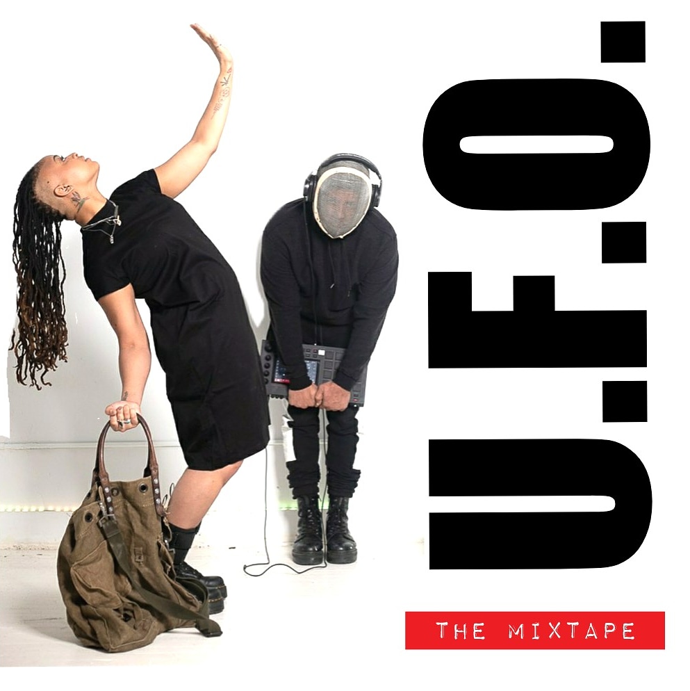 1.Tendayi on the left with long hair and shaved sides in a back dress and black boots leaning back facing sideways with one arm up to the sky leaning back holding a big green bag in the other hand. Greg is wearing a mask, black hoodie, and black pants leaning forward holding an MPC music machine with headphones on.