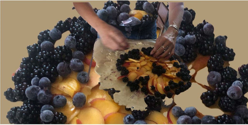 A graphic design with photos of blackberries, blueberries, and sliced peaches. In the center of the design, two hands arrange berries and sliced peaches on raw pastry. A galette? A pie? One hand wears a silver ring on their middle finger and a silver bracelet hangs on their wrist. The other hand is blurred in motion.