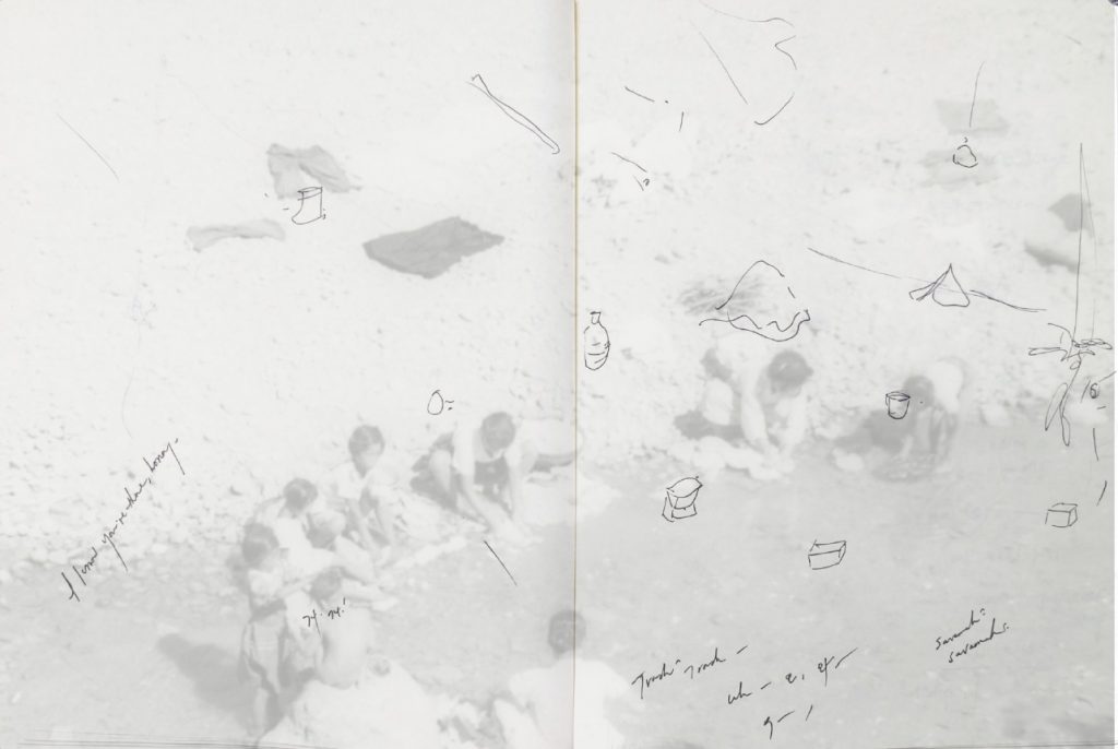 An overexposed black and white photo of a group of people crouching along the edge of a body of water. Layered over the photo are illegibly scribed pen ink notes and drawings of small shapes and objects. The center of the composition looks like the inside bind of a black notepad, as if scanned from the inside of a book.